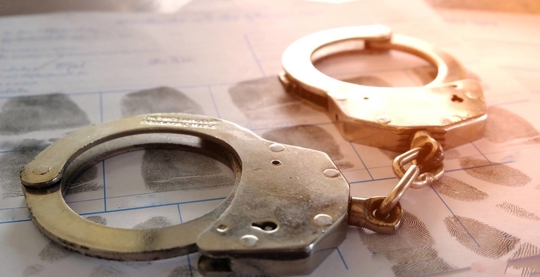 handcuffs on top of paper with fingerprints