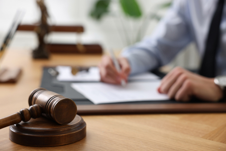 Attorney signing paperwork with gavel in front